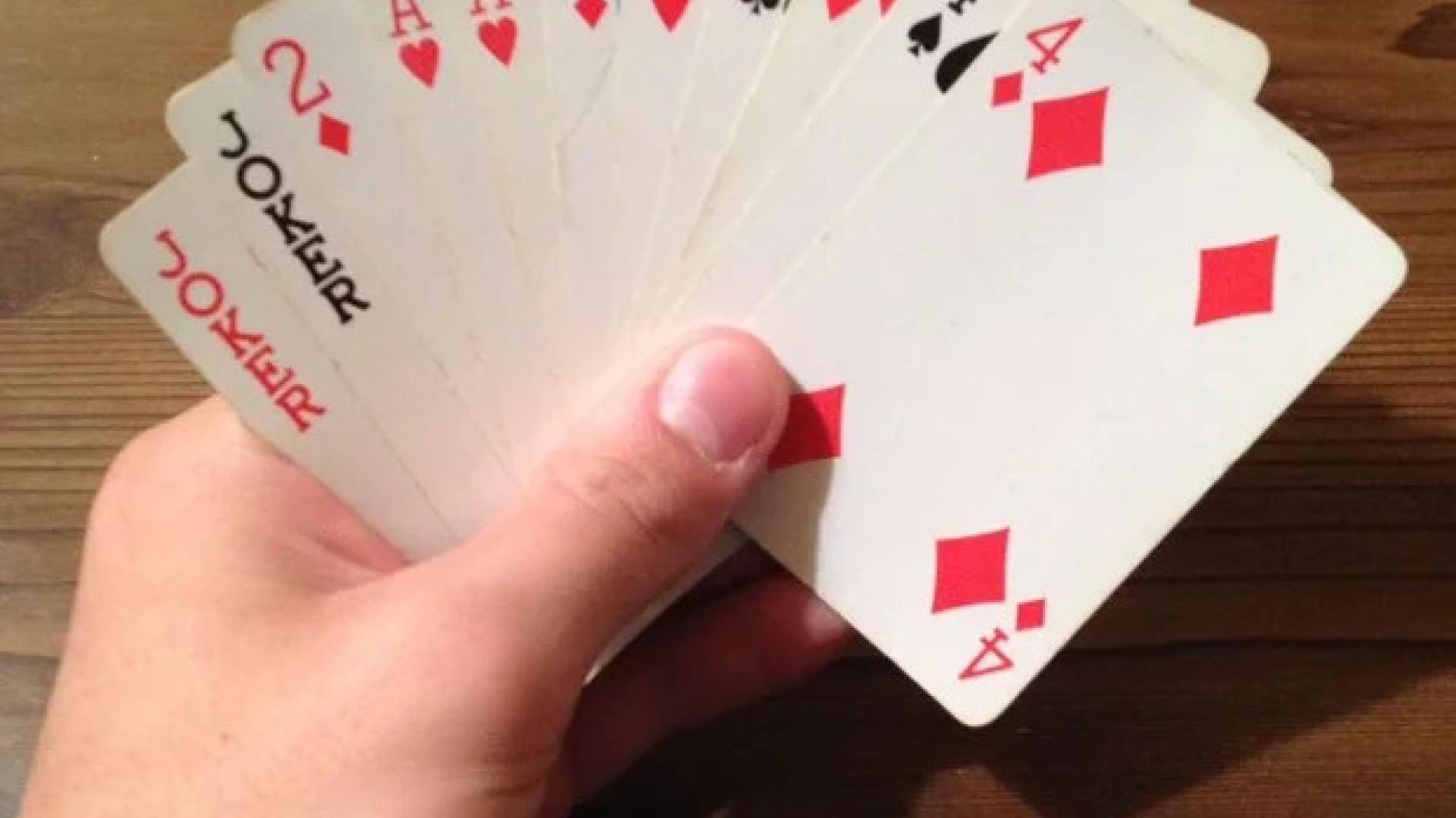 A hand holding playing cards, mostly red suits, fanned out.